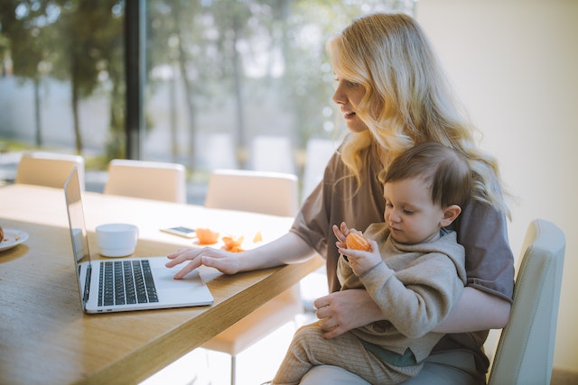 mother working on laptop with child on lap