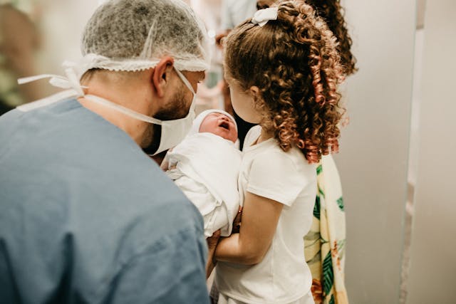 man and girl holding baby